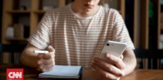 a14414fc young man writing something notebook while looking his smartphone og.jpg